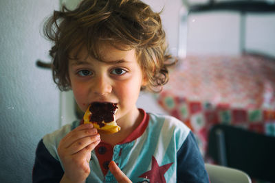 Portrait of boy eating rusk with strawberry jam at home