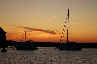 Sailboats in sea against sky during sunset