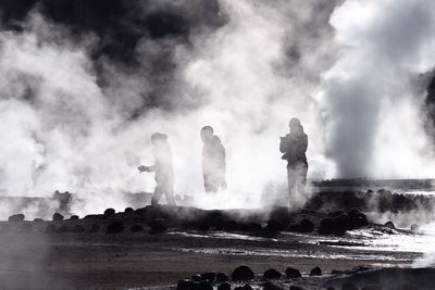 People at volcanic landscape against sky