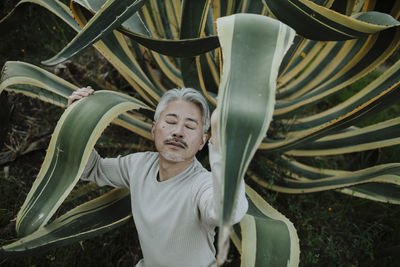 Mature man with eyes closed touching succulent plant