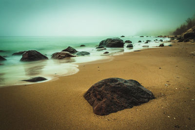 Surface level of rocks on beach against clear sky