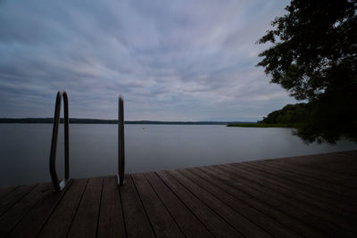 Wooden posts in lake against sky