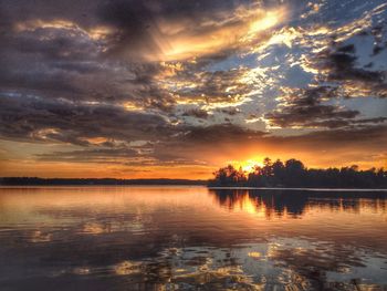 Scenic view of lake against cloudy sky during sunset