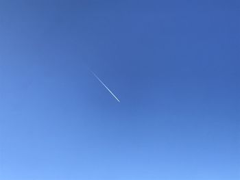 Low angle view of vapor trail against clear blue sky