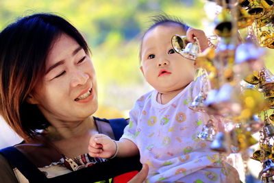 Mother looking at cute daughter by bells