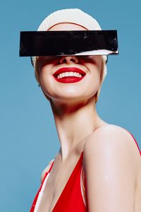 Portrait of young woman wearing hat against blue background