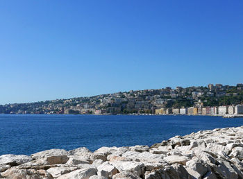 Sea by buildings against clear blue sky