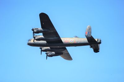 Low angle view of airplane flying against clear blue sky