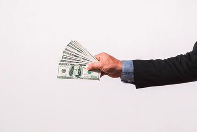 Cropped hand of person holding paper currency against white background