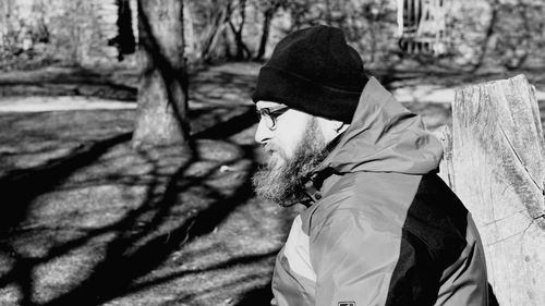 Side view of thoughtful bearded man in park at sunny day