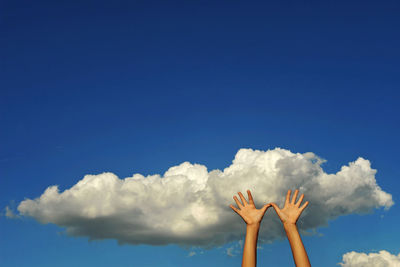 Low angle view of hands against sky