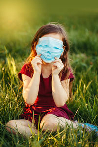 Girl wearing mask sitting on field