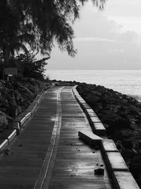 Empty footpath by sea against sky