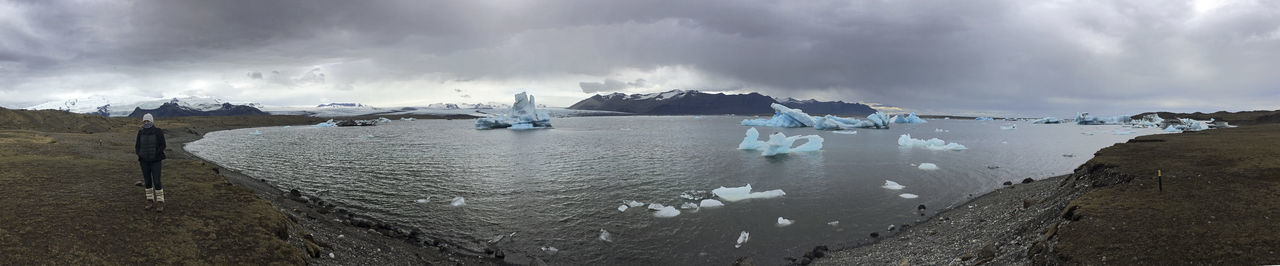 Panoramic view of people on snow covered landscape against sky