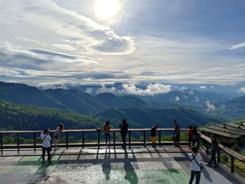 People at observation point by mountains against sky