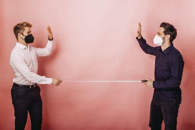 Man with arms raised standing against wall