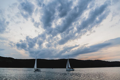 Sailboat sailing on sea against sky during sunset