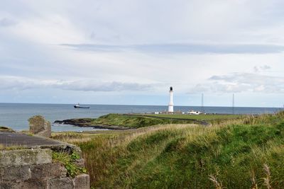 View of lighthouse on calm beach against sky