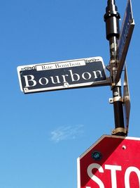 Low angle view of road sign against clear blue sky