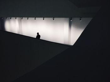 Silhouette of person standing in illuminated corridor