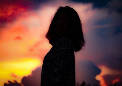 Portrait of silhouette woman standing against orange sky