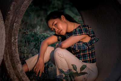 Young man sitting in concrete pipe