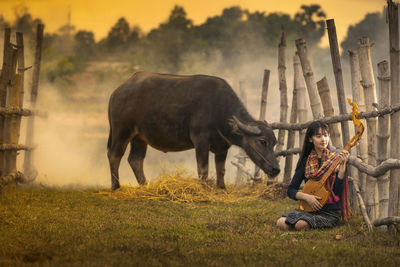 Woman with musical equipment sitting by bamboo railing