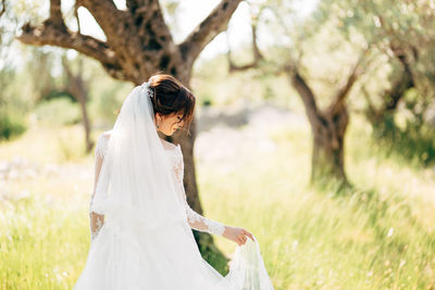 Rear view of bride standing against tree