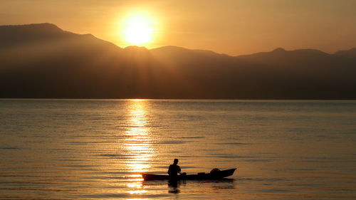 Silhouette boat in sea against sky during sunset