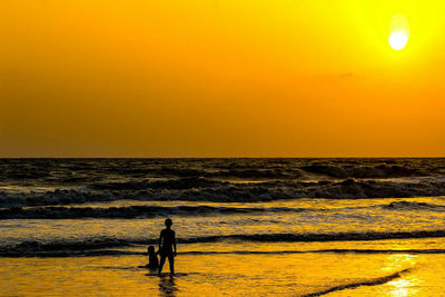 Silhouette woman on beach against sky during sunset