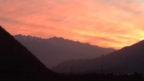 Scenic view of silhouette mountains against orange sky