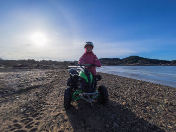 Man riding motorcycle on shore against sky