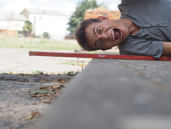 Portrait of young man screaming while lying on floor