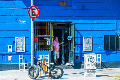 Man with bicycle on street against building