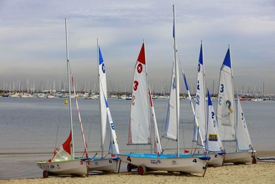 Sailboats moored on beach against sky