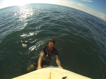 High angle view of man with surfboard in sea against sky