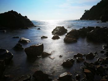 Rocks on sea shore against sky