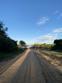 Road by trees against blue sky