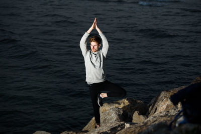 Man standing on rock by sea