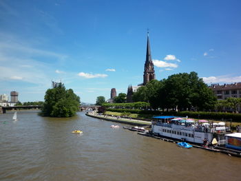 Boats in river by cathedral against sky in city