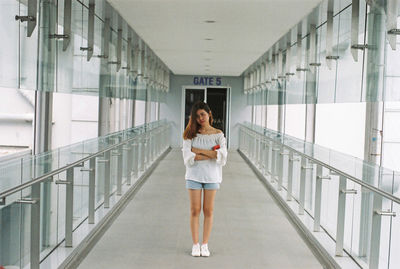 Portrait of young woman with arms crossed standing in corridor