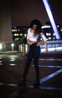 Full length of woman standing on road at night