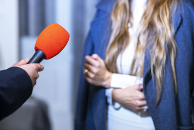 Midsection of woman holding microphone