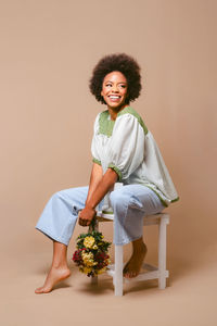 Portrait of young woman standing against wall