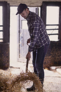 Full length of farmer shoveling hay in barn