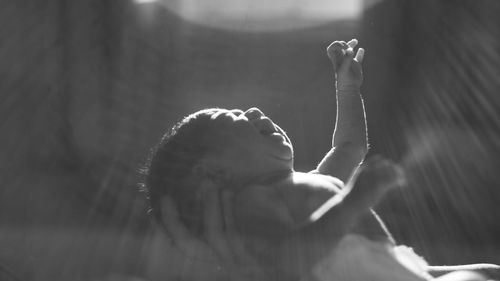 Baby boy with arms raised in darkroom