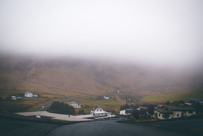 Winding road leading towards mountain during foggy weather