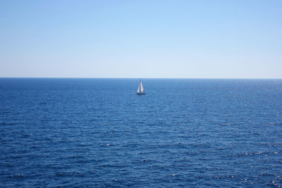 Sailboat sailing in sea against clear sky