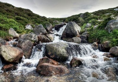 Scenic view of waterfall in forest against sky