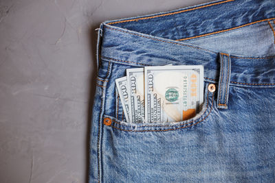 Directly above shot of paper currencies in jeans pocket on gray background
